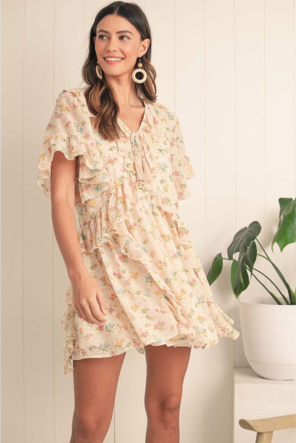 Embrace boho vibes with this apricot mini dress featuring a floral print and ruffle details. The tassel tie neckline adds a playful touch, perfect for summer days or relaxed evenings. A flattering V-neckline and flowing silhouette combine comfort and style effortlessly. The soft apricot hue pairs beautifully with the floral pattern for a feminine look.