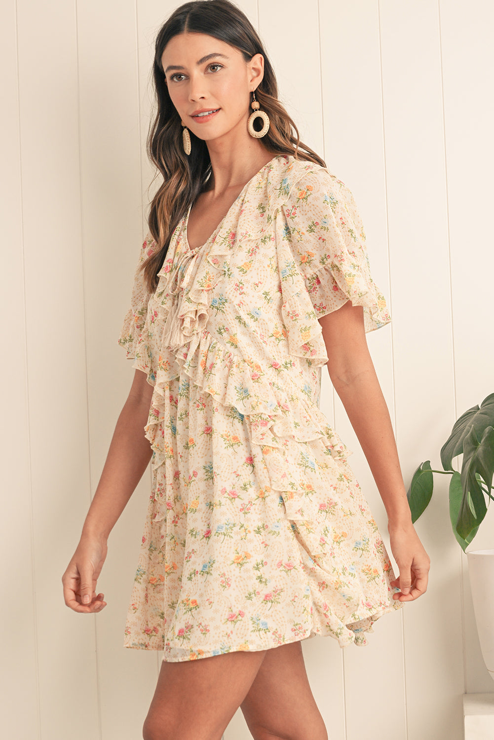 Embrace boho vibes with this apricot mini dress featuring a floral print and ruffle details. The tassel tie neckline adds a playful touch, perfect for summer days or relaxed evenings. A flattering V-neckline and flowing silhouette combine comfort and style effortlessly. The soft apricot hue pairs beautifully with the floral pattern for a feminine look.