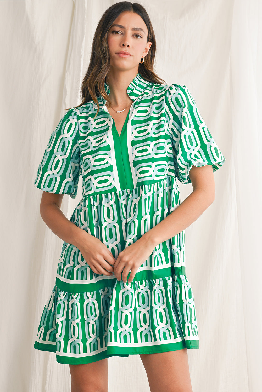 Vibrant green hue with an eye-catching abstract print, perfect for making a bold statement in any setting. V-neckline adds a touch of femininity, while puff sleeves bring a trendy and playful element to the design. Flirty mini length enhances the legs and silhouette, ideal for showcasing your style with confidence. Boho-inspired frill detailing along the neckline and hemline adds a touch of whimsy and charm to the overall look.