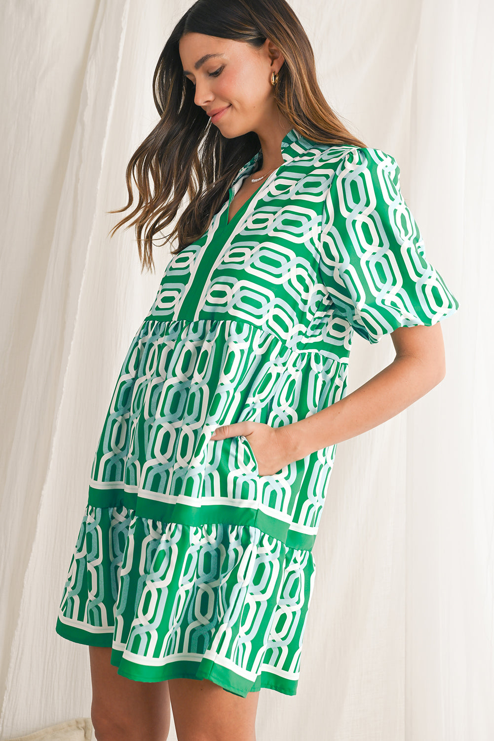 Vibrant green hue with an eye-catching abstract print, perfect for making a bold statement in any setting. V-neckline adds a touch of femininity, while puff sleeves bring a trendy and playful element to the design. Flirty mini length enhances the legs and silhouette, ideal for showcasing your style with confidence. Boho-inspired frill detailing along the neckline and hemline adds a touch of whimsy and charm to the overall look.