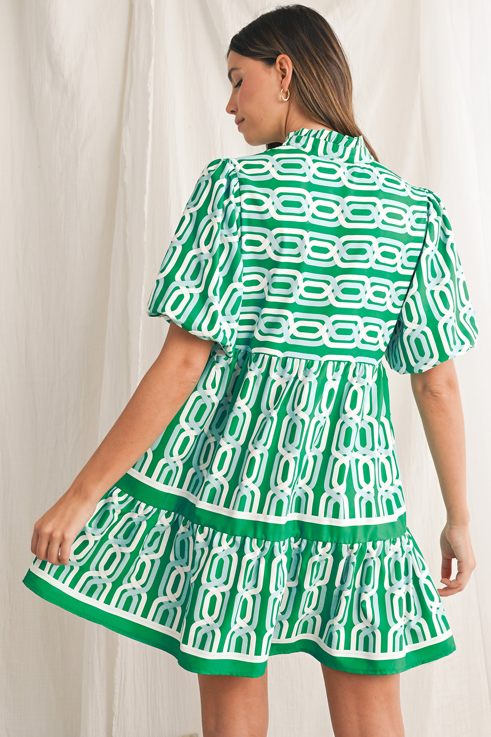 Vibrant green hue with an eye-catching abstract print, perfect for making a bold statement in any setting. V-neckline adds a touch of femininity, while puff sleeves bring a trendy and playful element to the design. Flirty mini length enhances the legs and silhouette, ideal for showcasing your style with confidence. Boho-inspired frill detailing along the neckline and hemline adds a touch of whimsy and charm to the overall look.