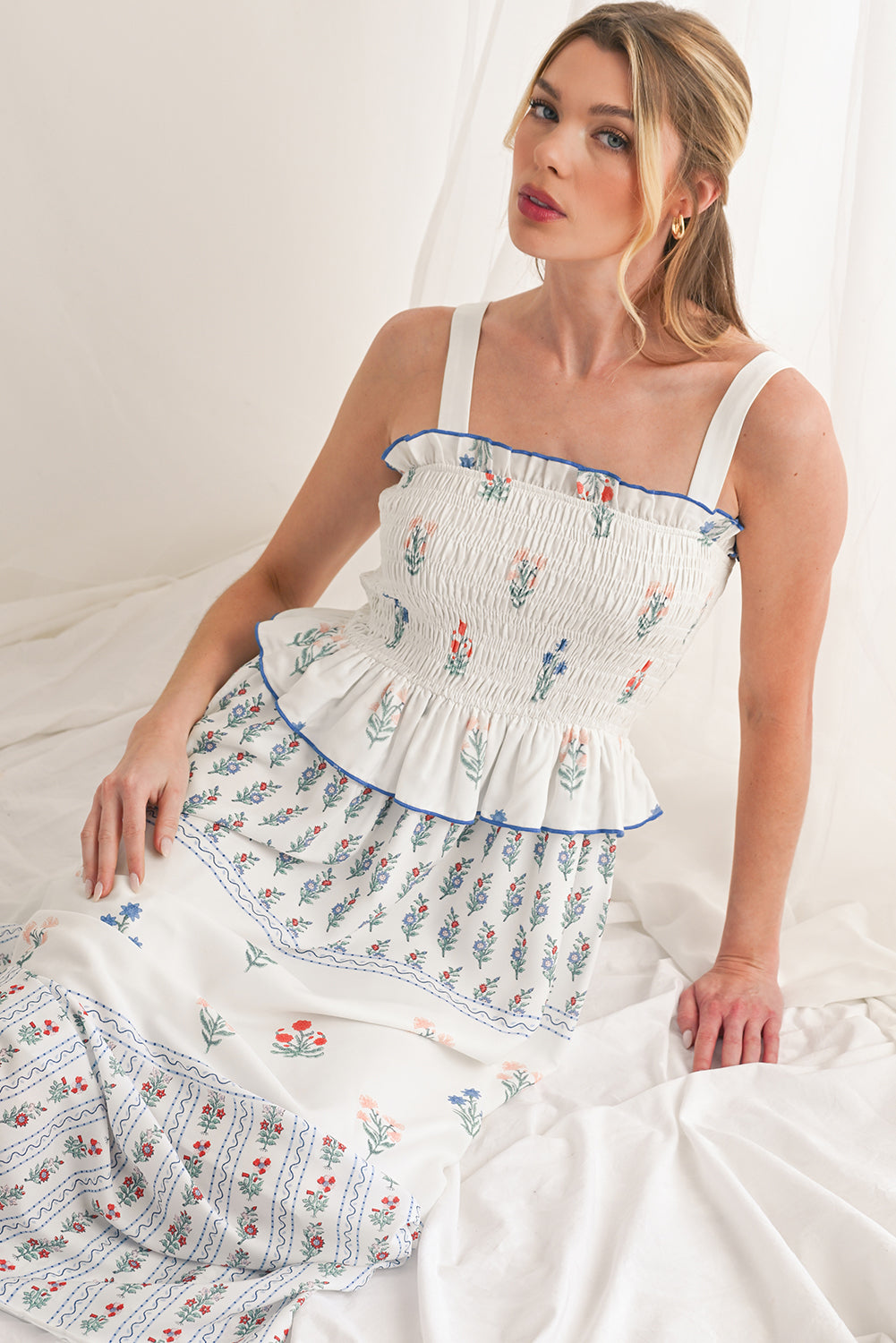 White Floral Print Boho Dress with elegant frill details for a stylish, feminine look. Smocked bodice ensures a flattering fit and all-day comfort. Flowing ruffle hem adds a romantic, bohemian touch. Fresh floral print on white, perfect for spring, summer, or casual occasions.